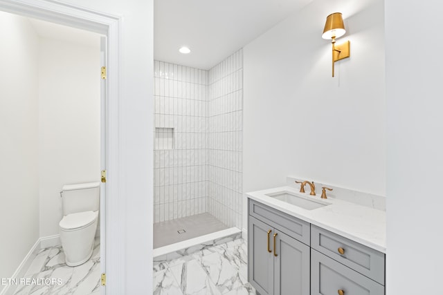 bathroom with vanity, toilet, and a tile shower