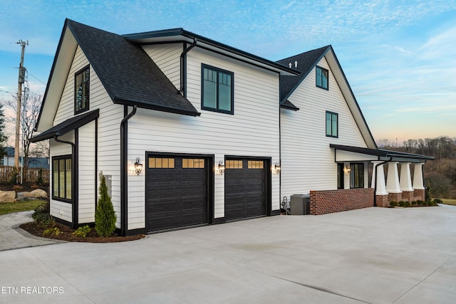 property exterior at dusk with a garage and central AC unit