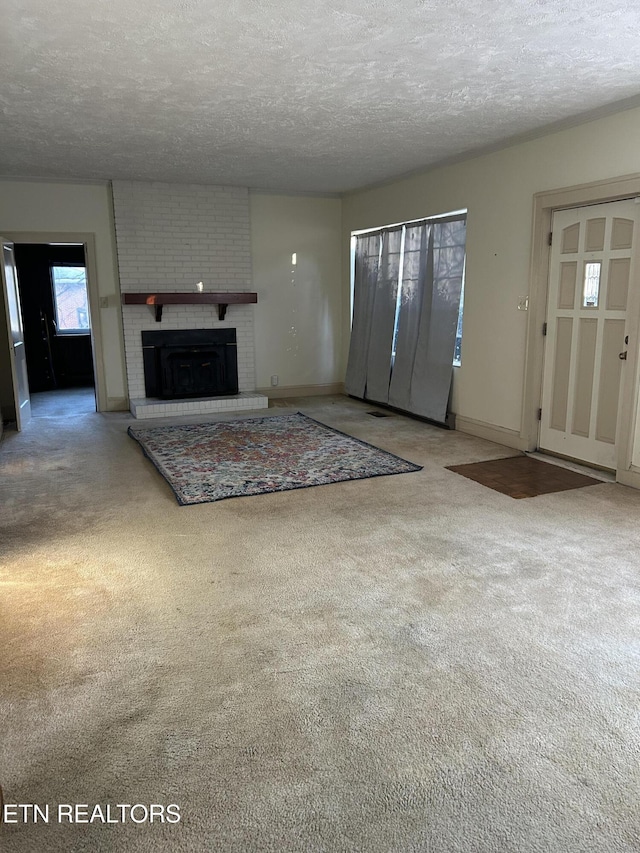 unfurnished living room with a textured ceiling, a brick fireplace, and carpet