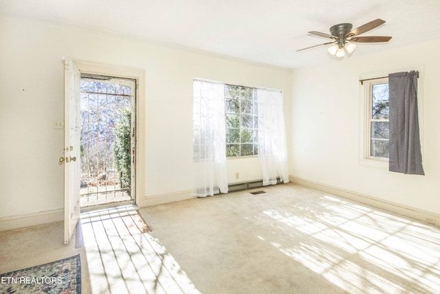 carpeted spare room with ceiling fan, crown molding, and plenty of natural light