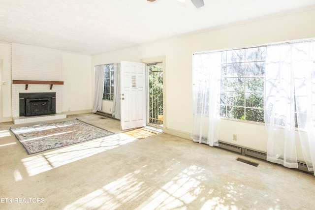 unfurnished living room featuring a brick fireplace, light colored carpet, and ceiling fan