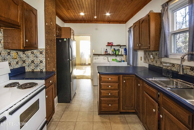 kitchen with wooden ceiling, backsplash, electric range, black fridge, and separate washer and dryer