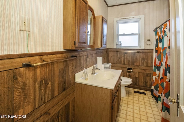 bathroom with crown molding, vanity, toilet, and wood walls