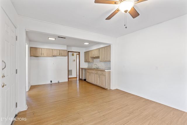 unfurnished living room featuring sink, light hardwood / wood-style floors, and ceiling fan