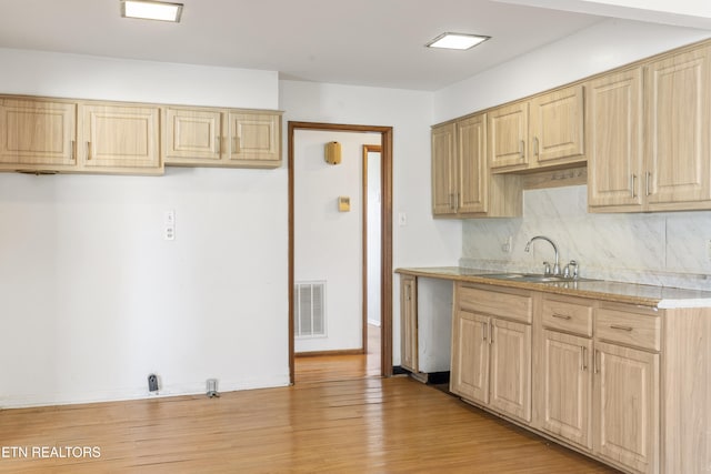 kitchen with decorative backsplash, sink, light brown cabinets, and light hardwood / wood-style floors