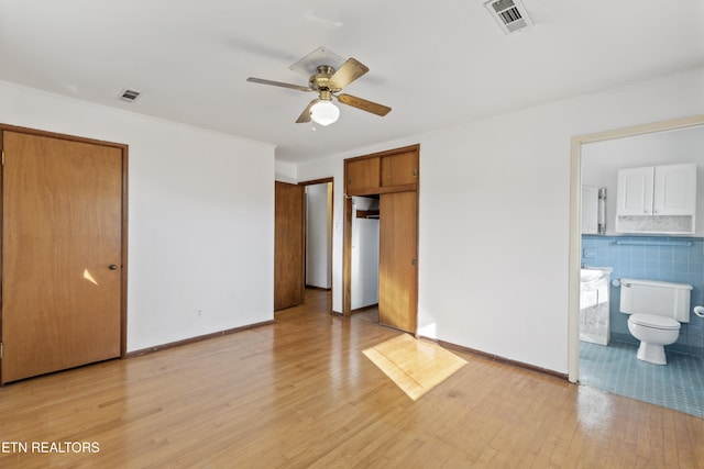 unfurnished bedroom with light hardwood / wood-style flooring, ensuite bath, and ceiling fan