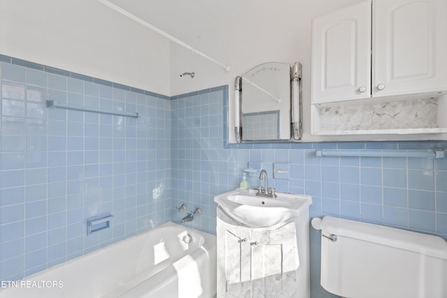 full bathroom with tile walls, toilet, tiled shower / bath, and vanity