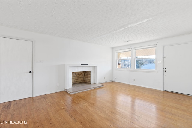 unfurnished living room with light wood-type flooring and a textured ceiling