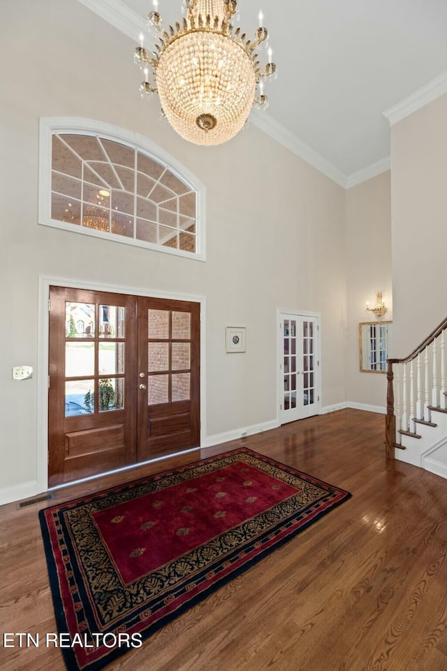 entryway featuring french doors, a towering ceiling, wood-type flooring, and crown molding