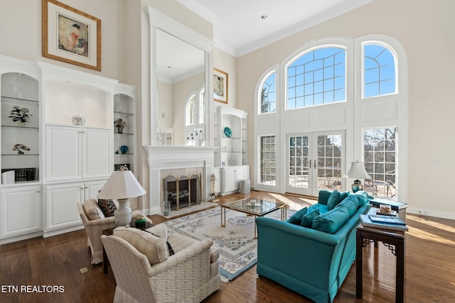 living room with crown molding, built in features, dark hardwood / wood-style flooring, and french doors