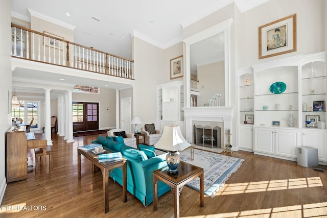 living room featuring a towering ceiling, built in features, dark hardwood / wood-style flooring, ornamental molding, and french doors