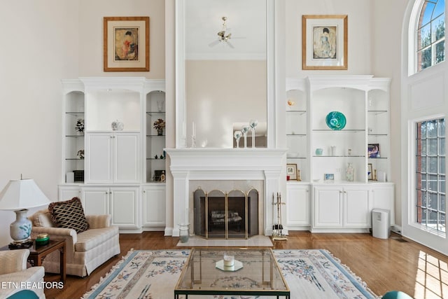 living room featuring hardwood / wood-style flooring, a high ceiling, a healthy amount of sunlight, and built in shelves