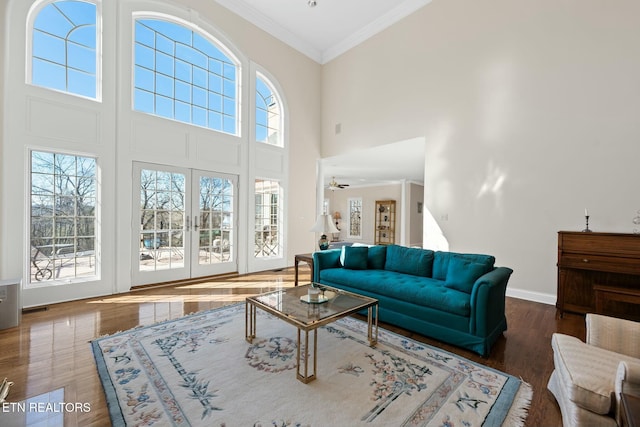 living room with crown molding, dark wood-type flooring, ceiling fan, and a high ceiling