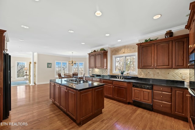 kitchen featuring hanging light fixtures, a kitchen island, stainless steel gas stovetop, and light hardwood / wood-style floors