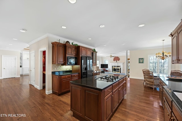 kitchen featuring dark wood-type flooring, black appliances, hanging light fixtures, a kitchen island, and backsplash