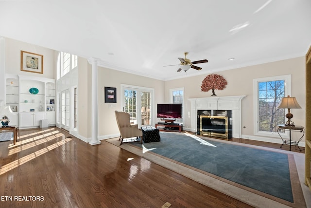 living room featuring decorative columns, crown molding, dark wood-type flooring, and built in features