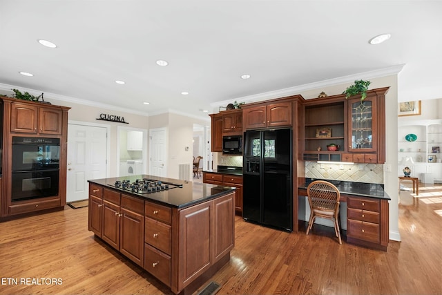 kitchen featuring washer / clothes dryer, a kitchen island, light hardwood / wood-style floors, and black appliances