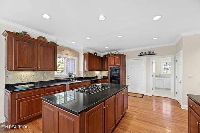 kitchen featuring sink, gas cooktop, black double oven, light hardwood / wood-style floors, and a kitchen island