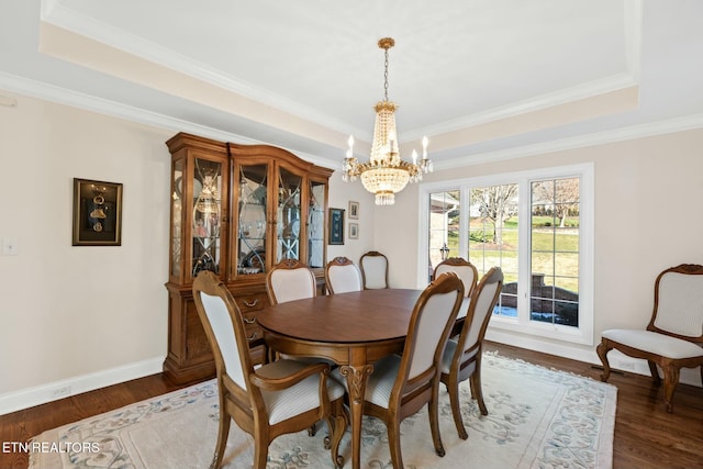 dining area with crown molding, an inviting chandelier, dark hardwood / wood-style flooring, and a tray ceiling