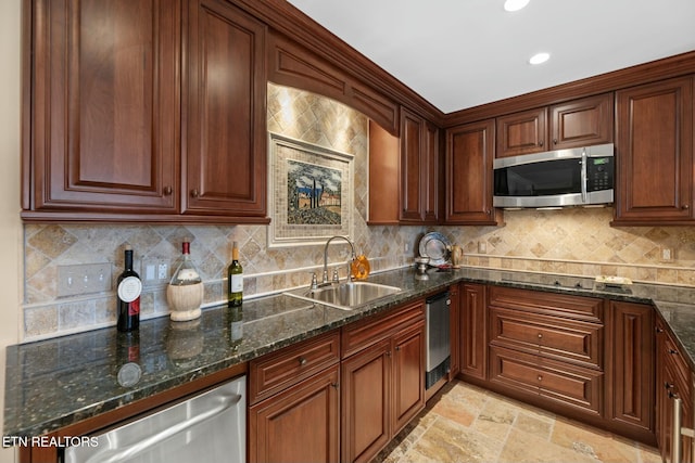 kitchen with backsplash, appliances with stainless steel finishes, sink, and dark stone countertops