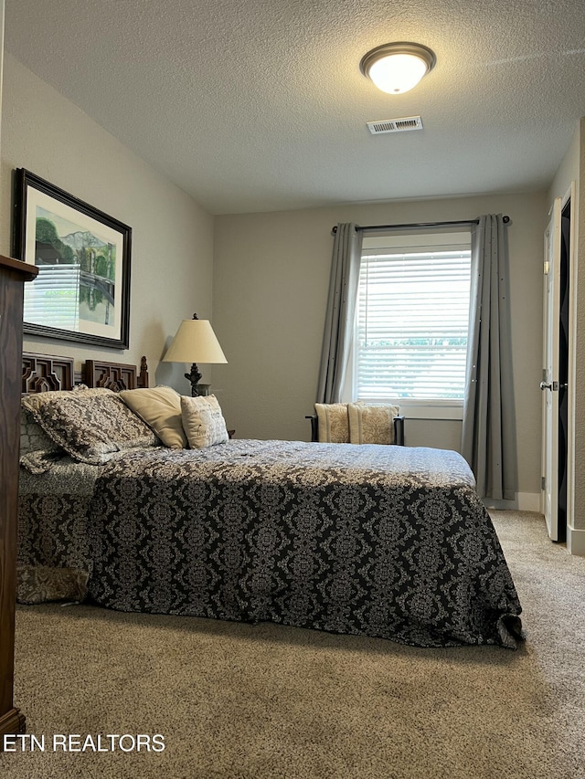 bedroom featuring a textured ceiling and light carpet