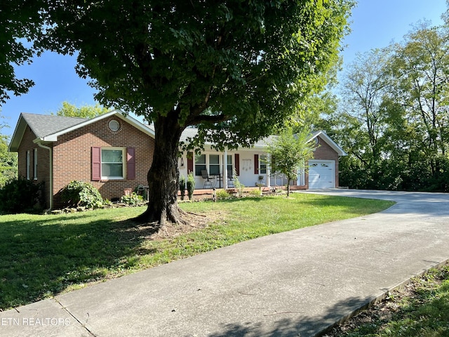 single story home with covered porch, a garage, and a front lawn