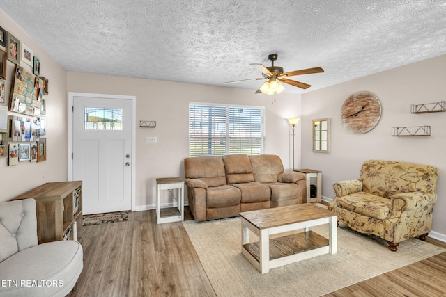 living room with ceiling fan, a textured ceiling, and light wood-type flooring