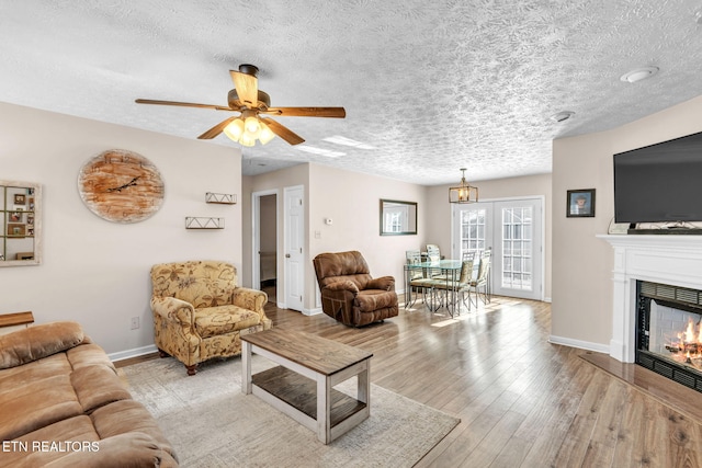 living room featuring light hardwood / wood-style floors, a textured ceiling, and ceiling fan