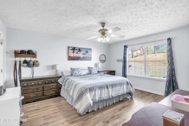 bedroom featuring a textured ceiling, ceiling fan, and light hardwood / wood-style flooring