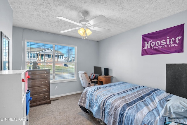 carpeted bedroom featuring ceiling fan and a textured ceiling