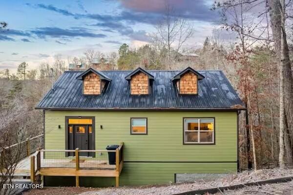 back house at dusk featuring a wooden deck