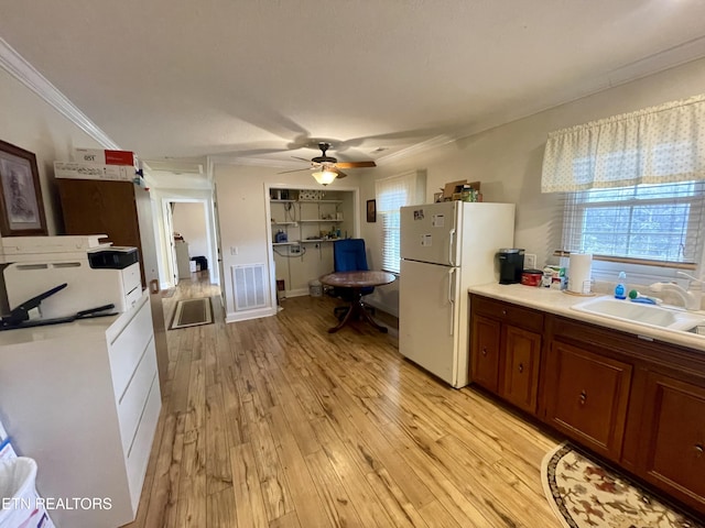 kitchen featuring white refrigerator, crown molding, sink, and light hardwood / wood-style flooring