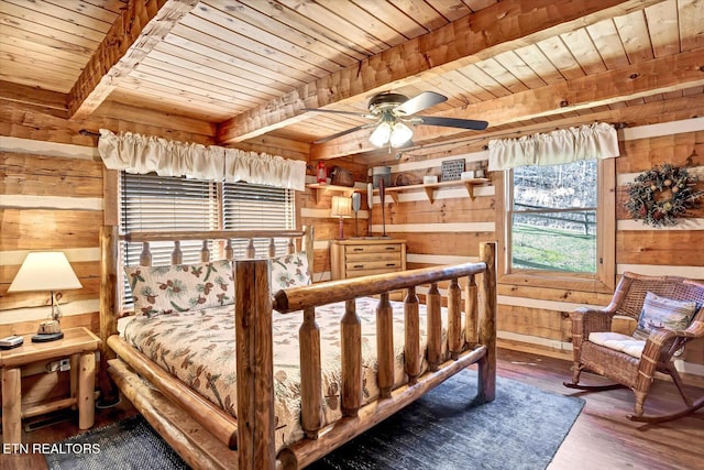 bedroom with beam ceiling, hardwood / wood-style flooring, and wooden walls