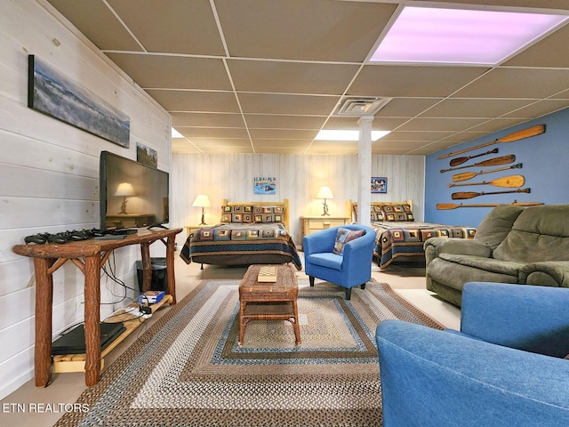 living room featuring a drop ceiling and wooden walls