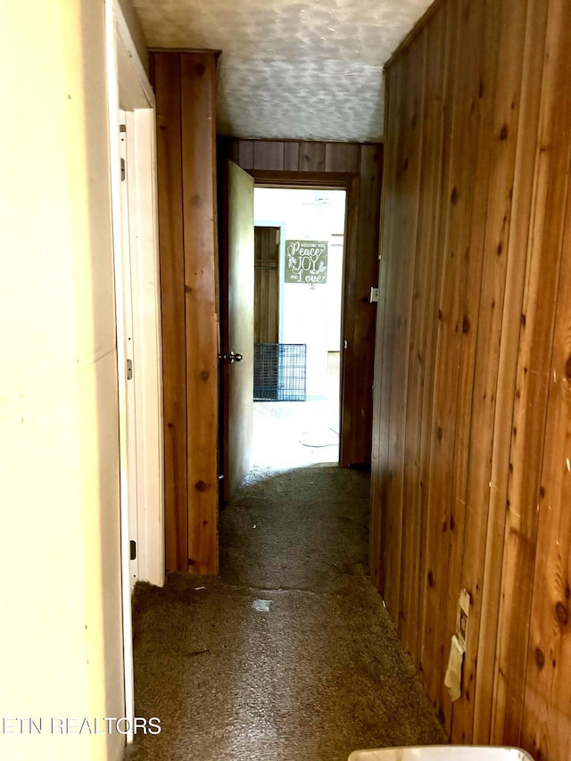 hall with a textured ceiling and wooden walls