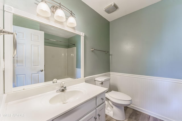 bathroom with vanity, wood-type flooring, toilet, and a shower