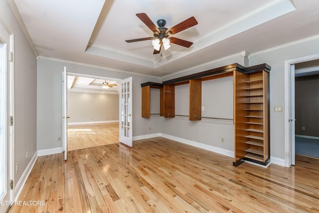 unfurnished bedroom featuring french doors, light hardwood / wood-style flooring, ornamental molding, a raised ceiling, and ceiling fan