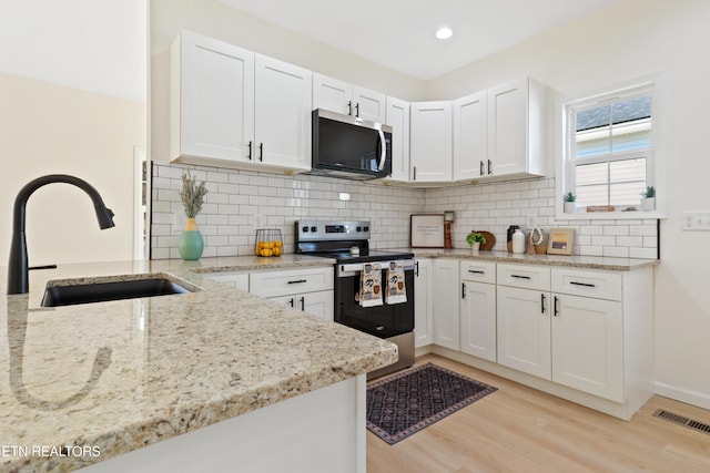 kitchen with white cabinetry, light hardwood / wood-style floors, stainless steel appliances, light stone counters, and sink