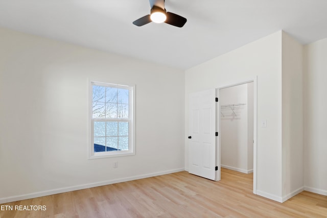 unfurnished bedroom with ceiling fan, a walk in closet, a closet, and light hardwood / wood-style floors