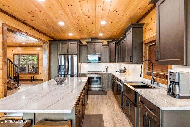 kitchen with a kitchen island, light wood-type flooring, light stone countertops, wood ceiling, and stainless steel appliances