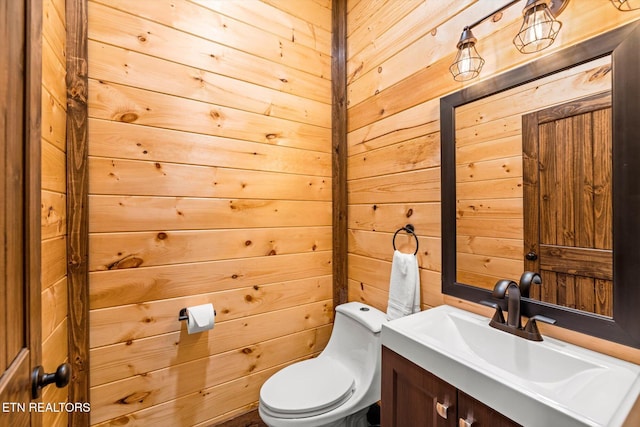 bathroom with toilet, vanity, and wood walls