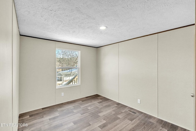 spare room with a textured ceiling and light wood-type flooring