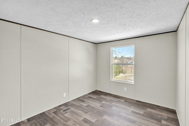 spare room with light hardwood / wood-style floors and a textured ceiling