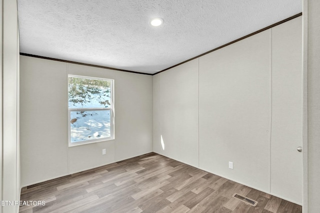 unfurnished room featuring light hardwood / wood-style flooring and a textured ceiling