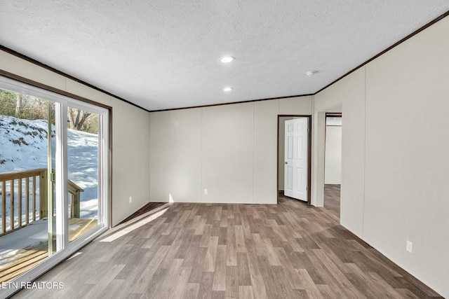 spare room featuring ornamental molding, light wood-type flooring, and a textured ceiling