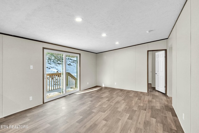 unfurnished room featuring light hardwood / wood-style flooring, ornamental molding, and a textured ceiling