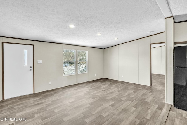 unfurnished living room featuring ornamental molding, light hardwood / wood-style floors, and a textured ceiling