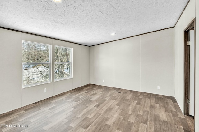 unfurnished room with light wood-type flooring and a textured ceiling