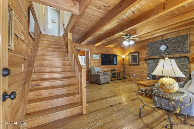 interior space with ceiling fan, light hardwood / wood-style floors, beamed ceiling, wooden walls, and wood ceiling