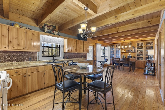 dining space with light hardwood / wood-style flooring, an inviting chandelier, beam ceiling, and plenty of natural light